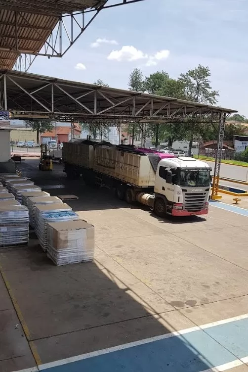 Caminhão Scania carregado na Comfrio Soluções Logísticas. Captura de tela mostra empilhadeira e pallets. Logística e transporte de carga.